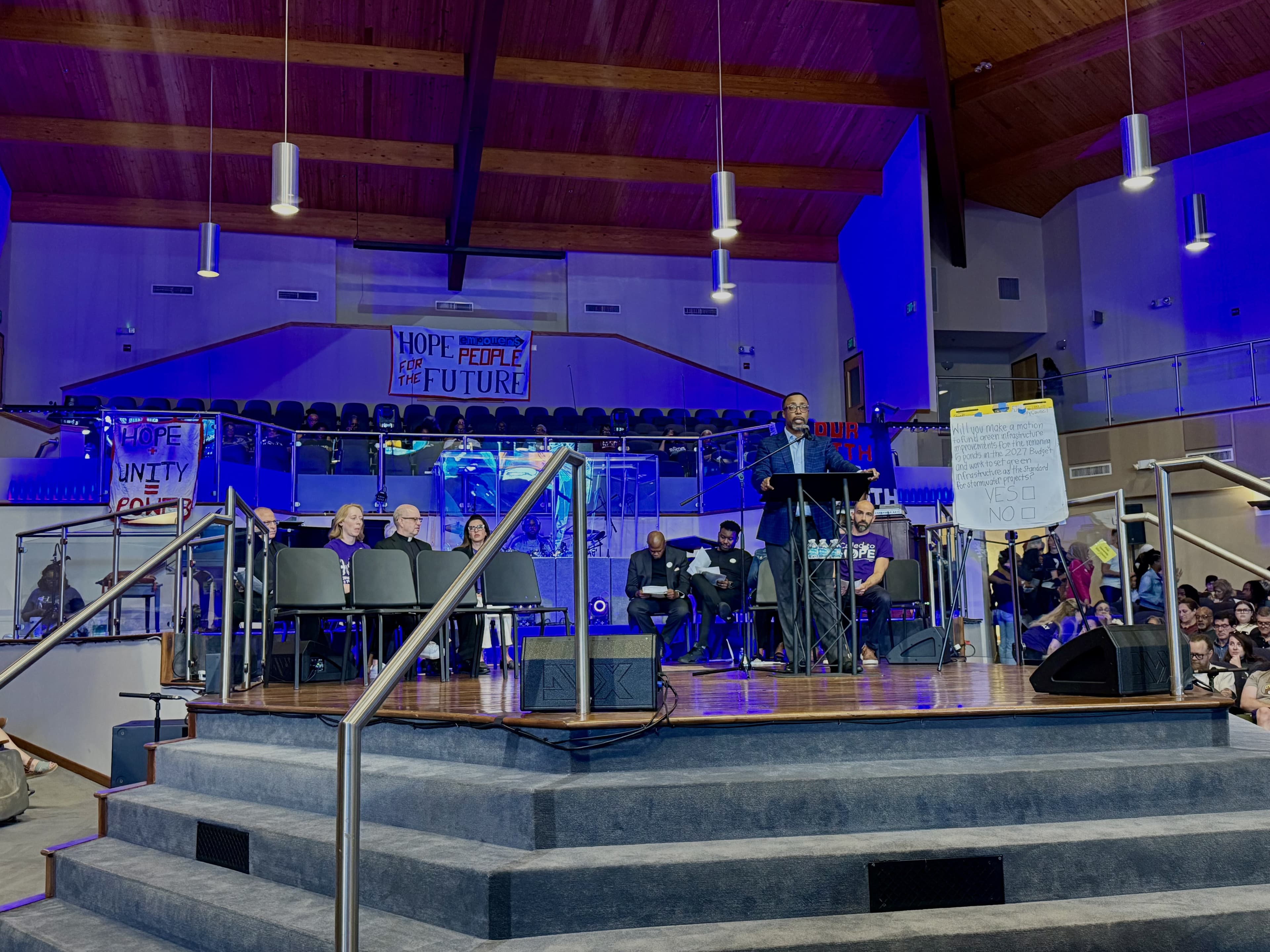 People speaking and sitting on stage in front of an audience in a church