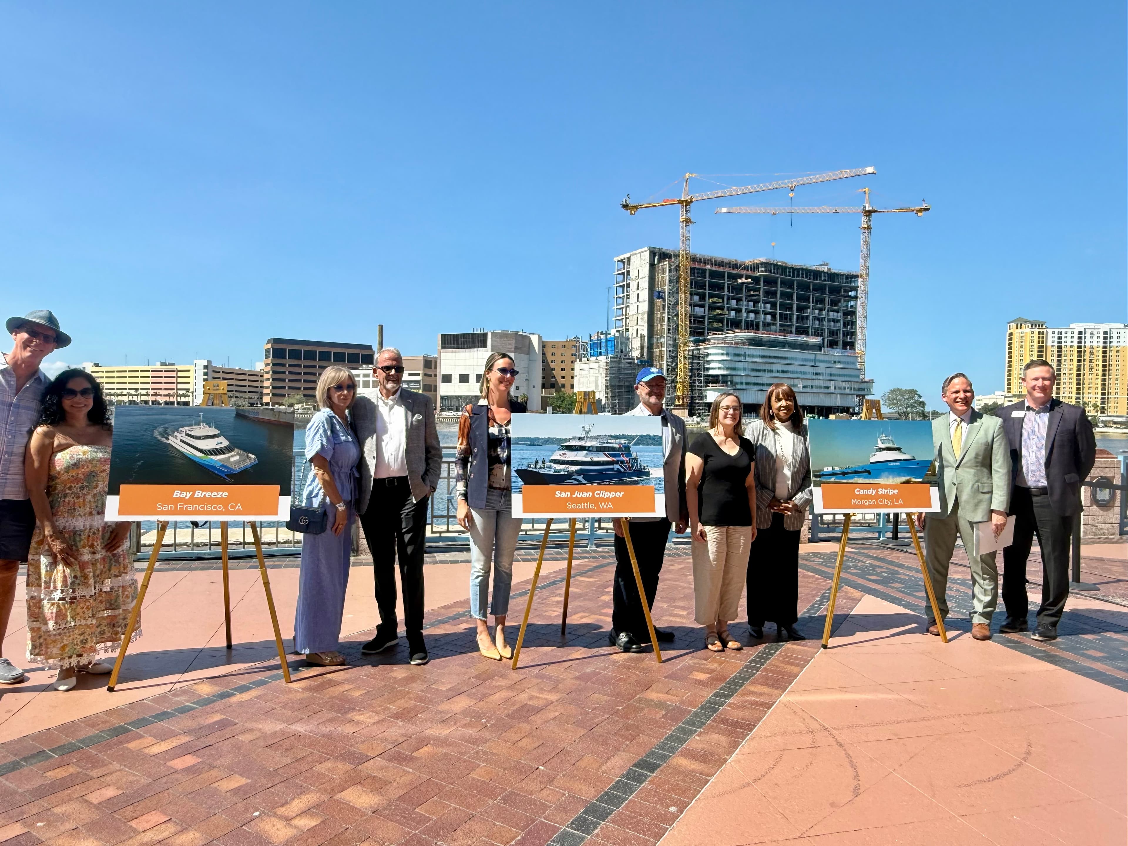 10 people standing around three large displays of ferry boat options in Tampa
