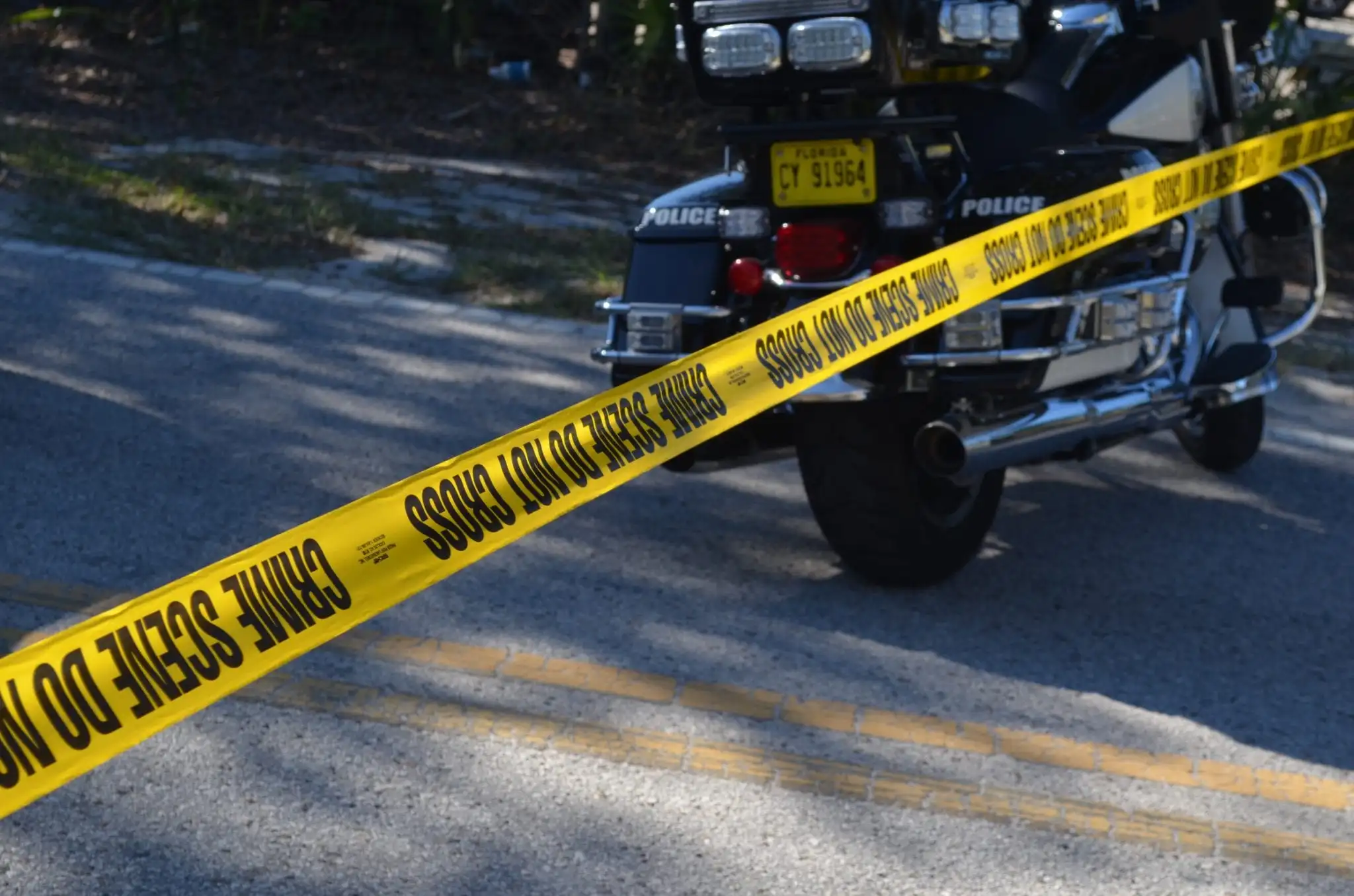 Crime scene do not cross yellow tape with motorcycle in back