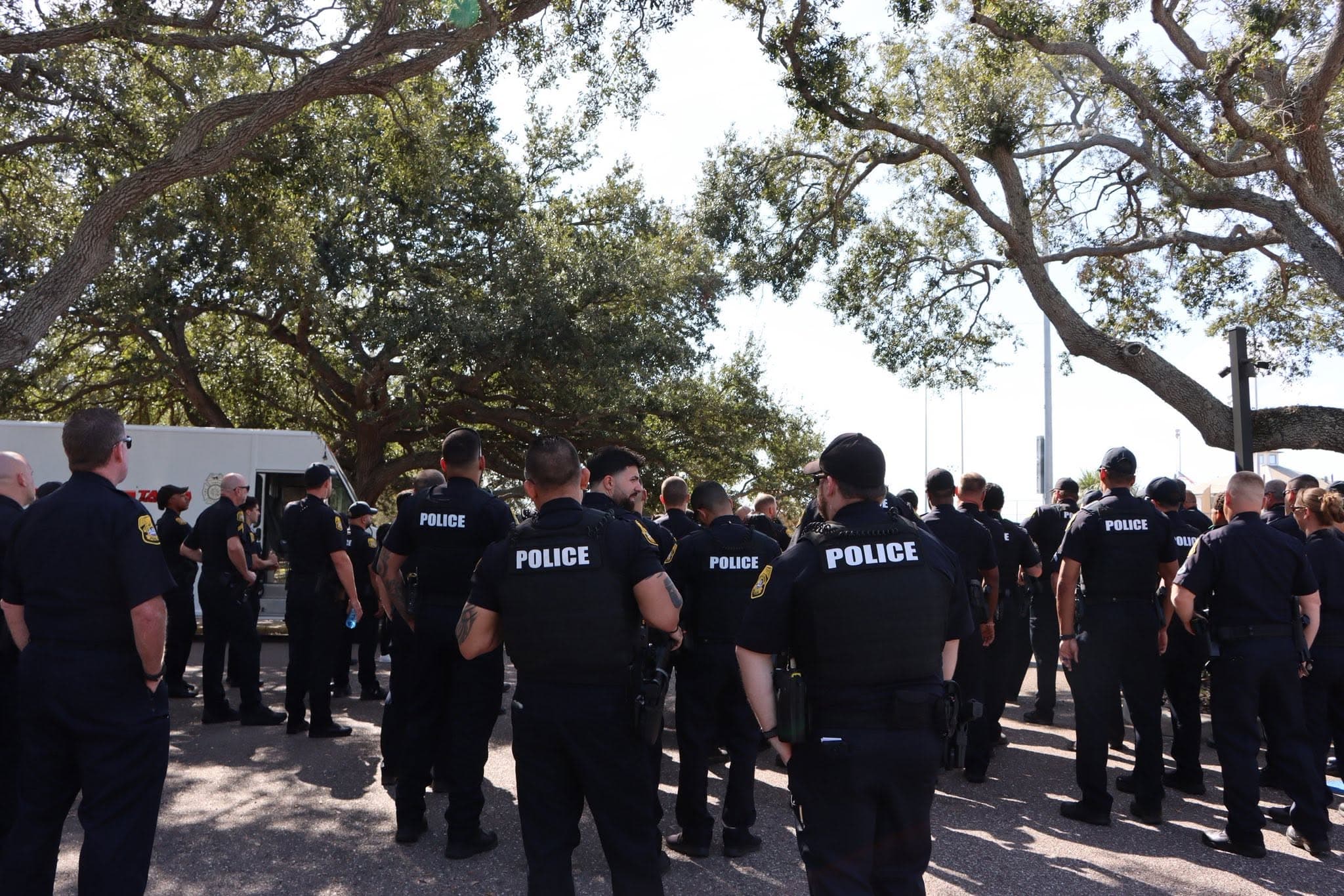 A bunch of police standing on the street in uniform