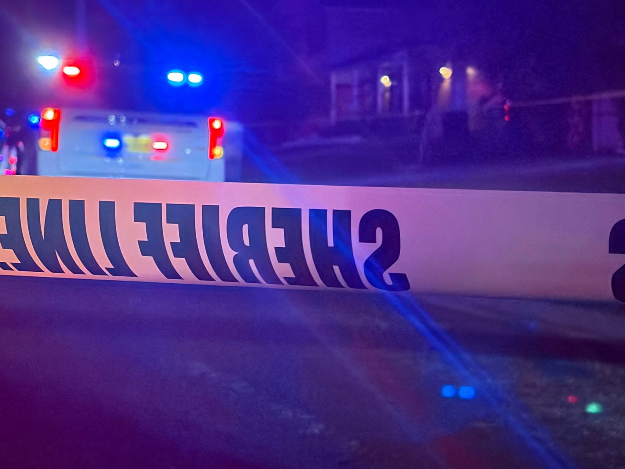 Sheriff tape for a crime scene with cop lights in background