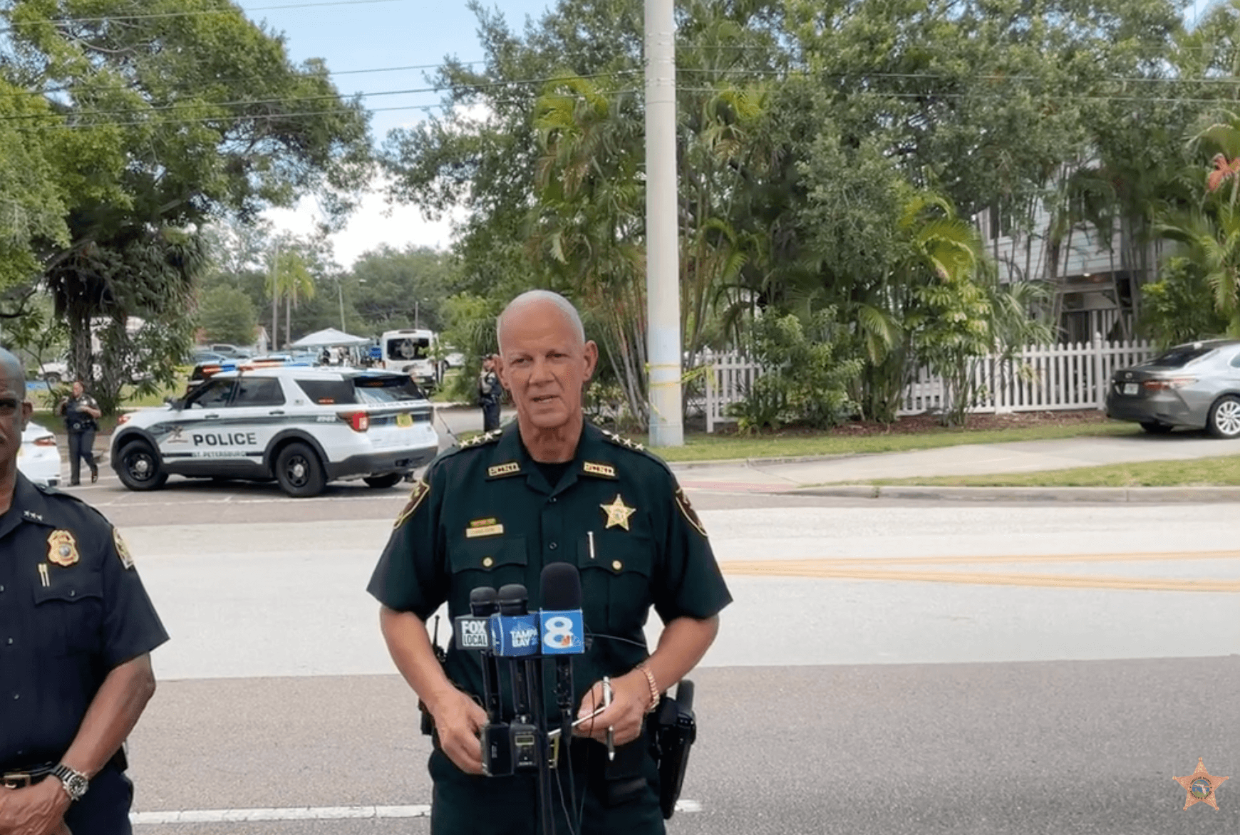 police officer talking into microphones at crime scene