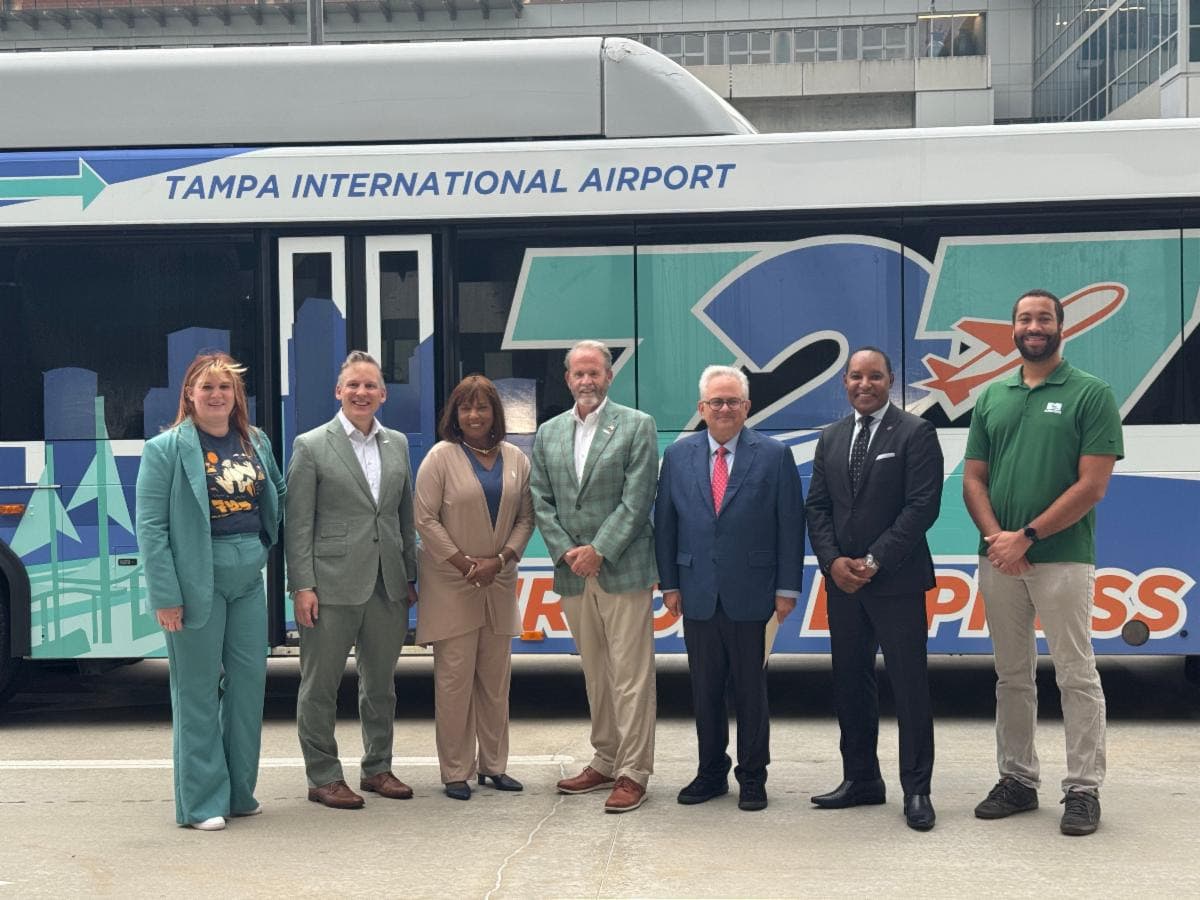 seven people smiling in front of a bus