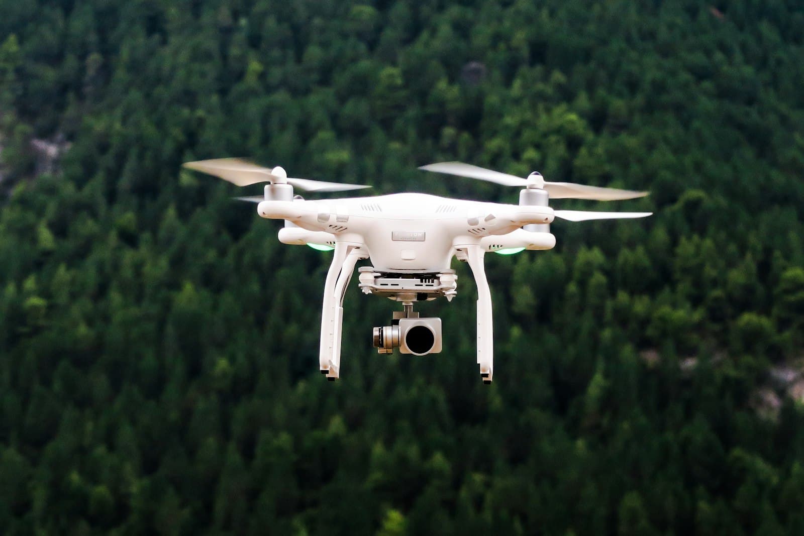 A white quadcopter drone flying against a blue sky
