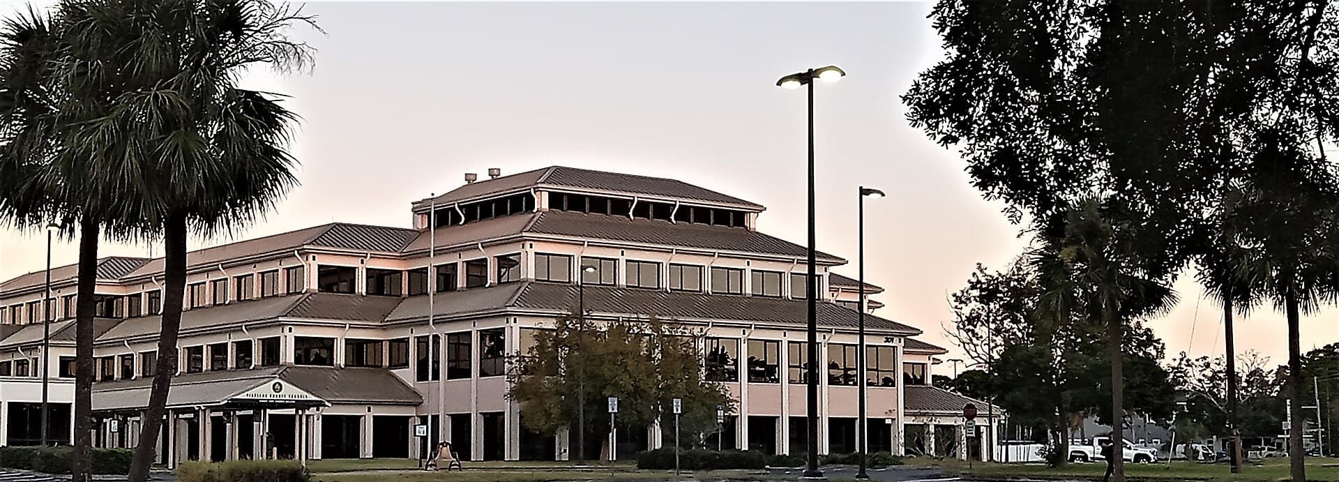 Pinellas County Schools administration building in Largo at dusk, framed by palm trees